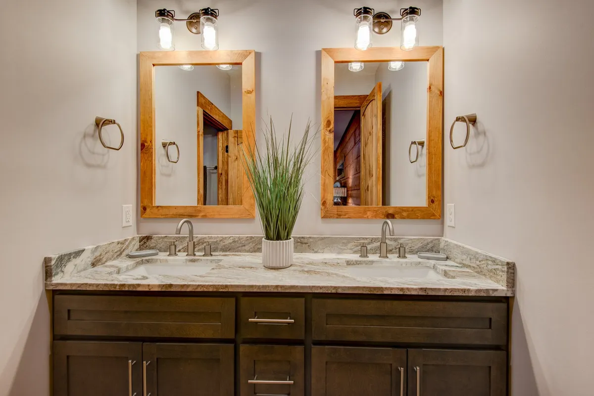A bathroom with a double granite vanity, two mirrors, and a decorative plant. The space is organized and inviting, exuding a spa-like ambiance perfect for self-care and daily routines.