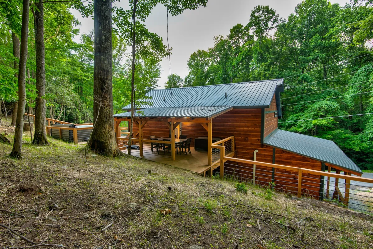 A spacious wooden deck with a large dining table surrounded by trees, offering plenty of room for family gatherings, outdoor meals, and group activities. The tranquil setting is ideal for both daytime and evening enjoyment.