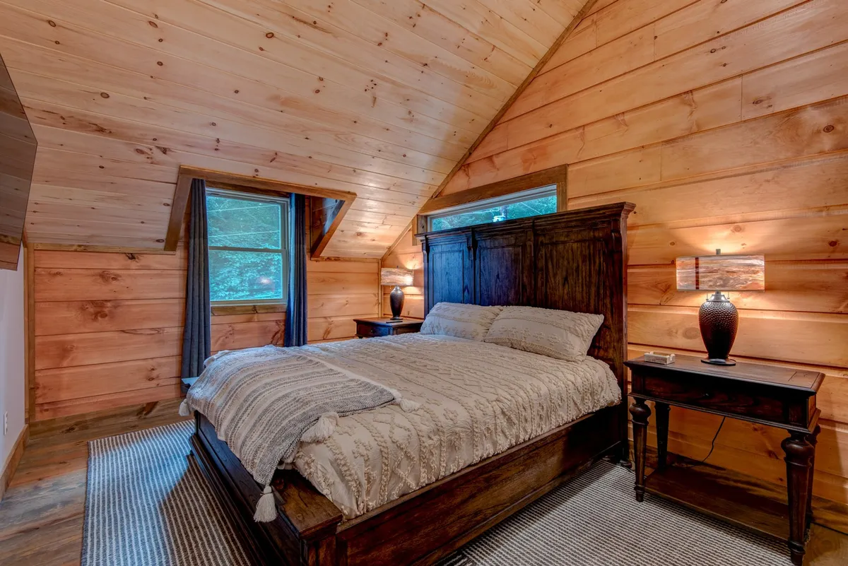 A tranquil bedroom scene featuring a plush bed with soft blankets, a nightstand, and large windows letting in natural light. The mood is restful and inviting, ideal for relaxation and a rejuvenating night's sleep.