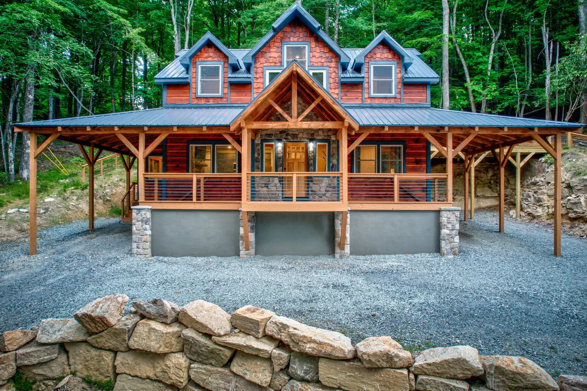 A welcoming wooden porch with a stone facade, large windows, and a sloped roof, surrounded by nature. The porch space suggests a place to relax after a day of mountain sports or to gather before heading out for new adventures.