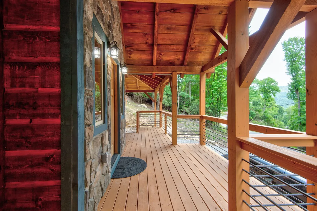 The tranquil wooden deck is surrounded by lush greenery, offering an ideal spot for relaxing, socializing, or enjoying nature. The setup suggests a seamless blend of indoor and outdoor living, perfect for group activities and unwinding after a day of adventure.