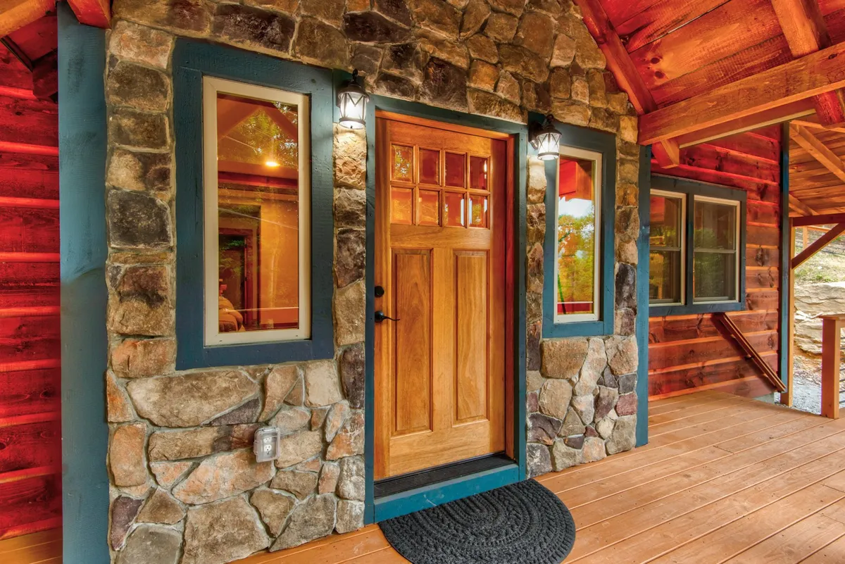 This image focuses on the cozy, welcoming entryway of the cabin, with a stone facade, wood-framed windows, and a porch area. It hints at the inviting atmosphere guests will experience right from arrival, reinforcing the idea of a private, exclusive retreat for groups.